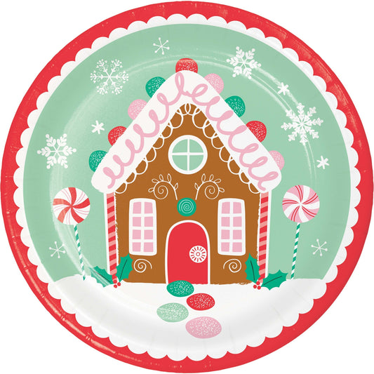 Gingerbread house design on a round paper plate with festive snowflakes.