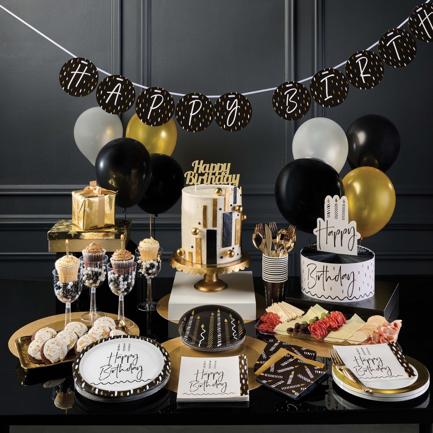 Golden Wishes paper plates, napkins and decorations displayed on a table