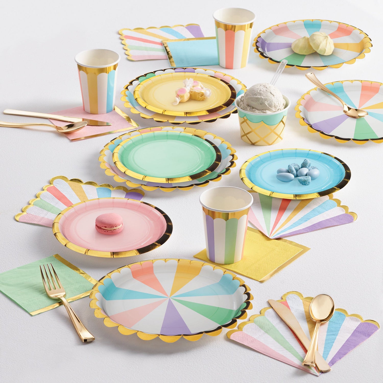 Pastel Celebrations Party Supplies. Pastel colored paper plates, napkins, and cups displayed on a table with sweet treats