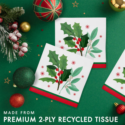 Christmas-themed paper napkins with holly design. Napkins are shown on a green background with festive decorations.