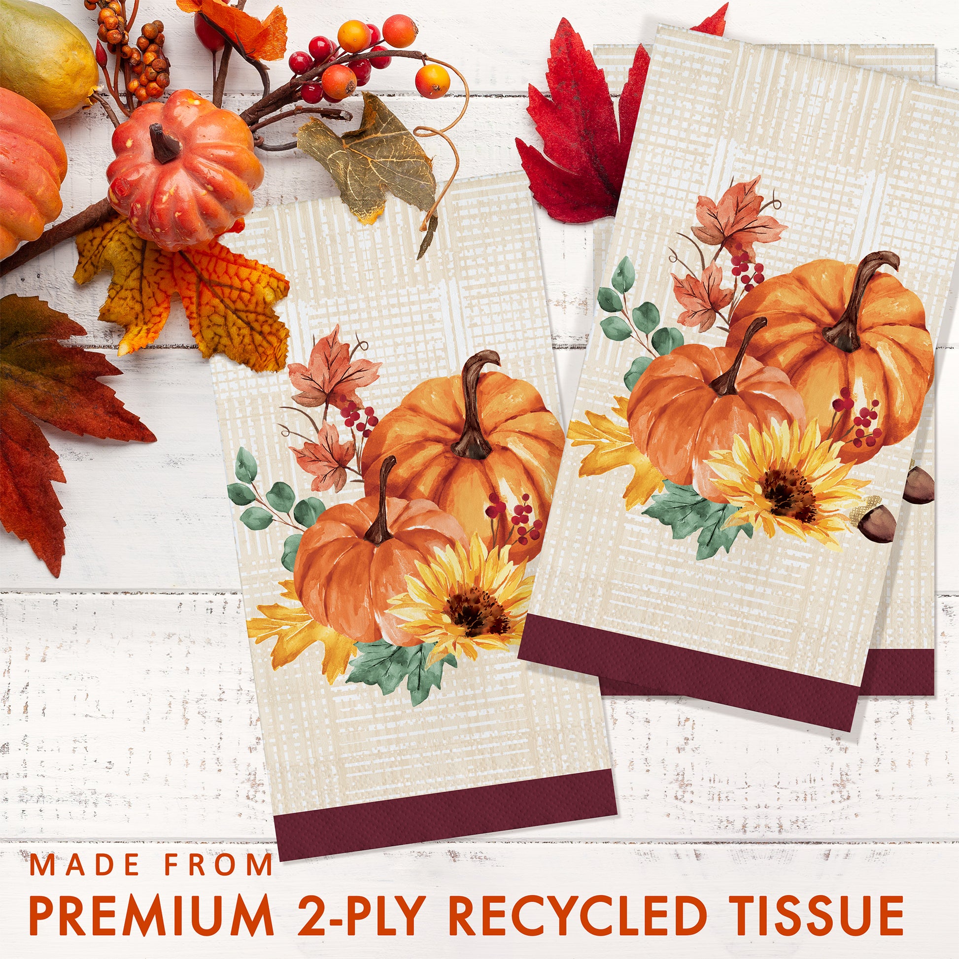 Fall Feast Dinner Napkins 192 ct. Two decorative paper napkins with pumpkin and leaf designs on a white wooden surface with autumn elements.