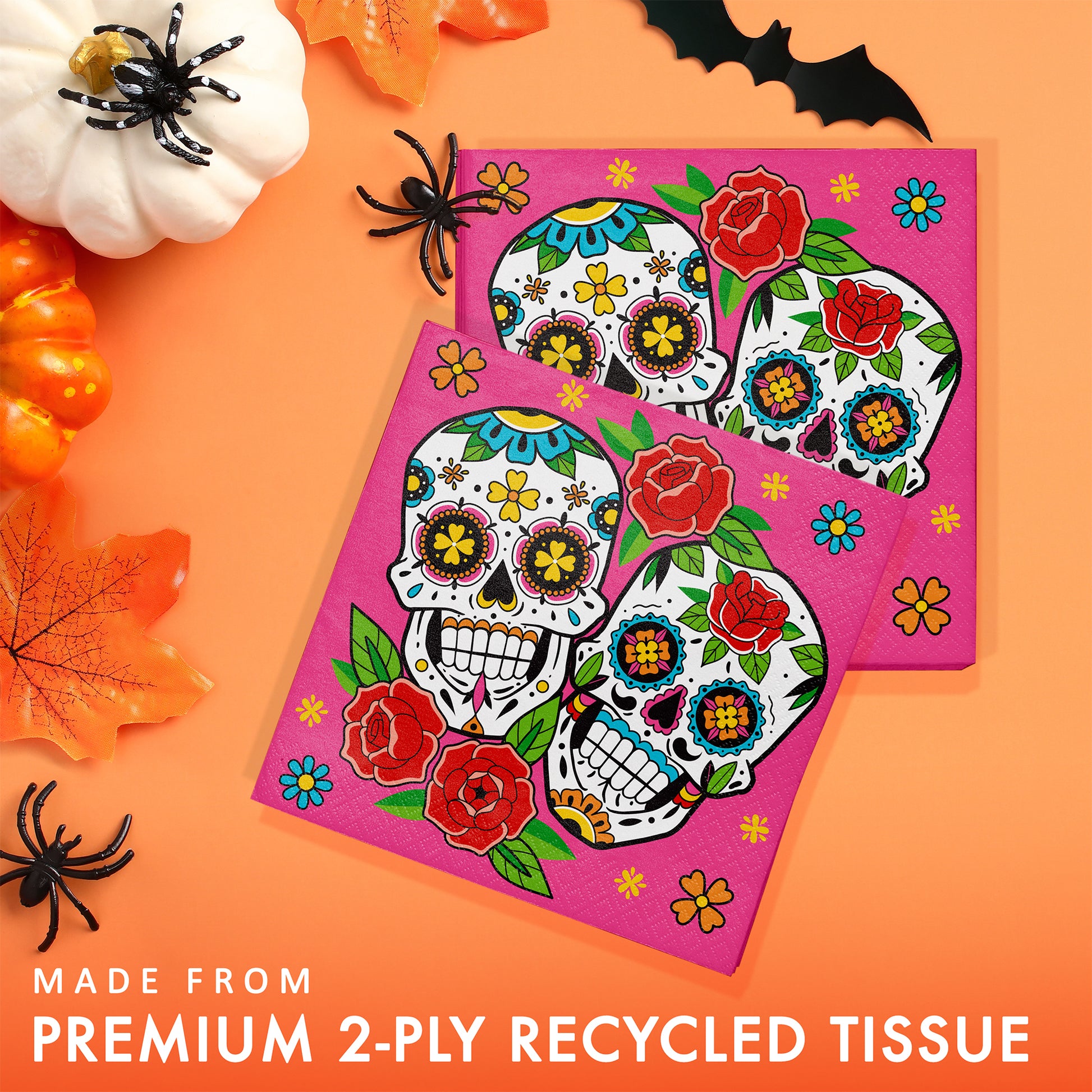 Skelebration Luncheon Napkins 192 ct. Colorful sugar skull design on pink tissue paper with Halloween decorations on an orange background.