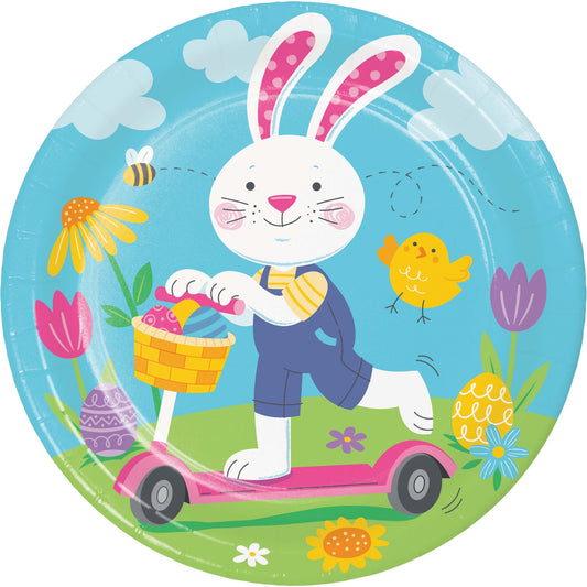 Round paper plate with a cartoon bunny riding a scooter, holding an Easter basket, surrounded by flowers and a chick on a blue background.
