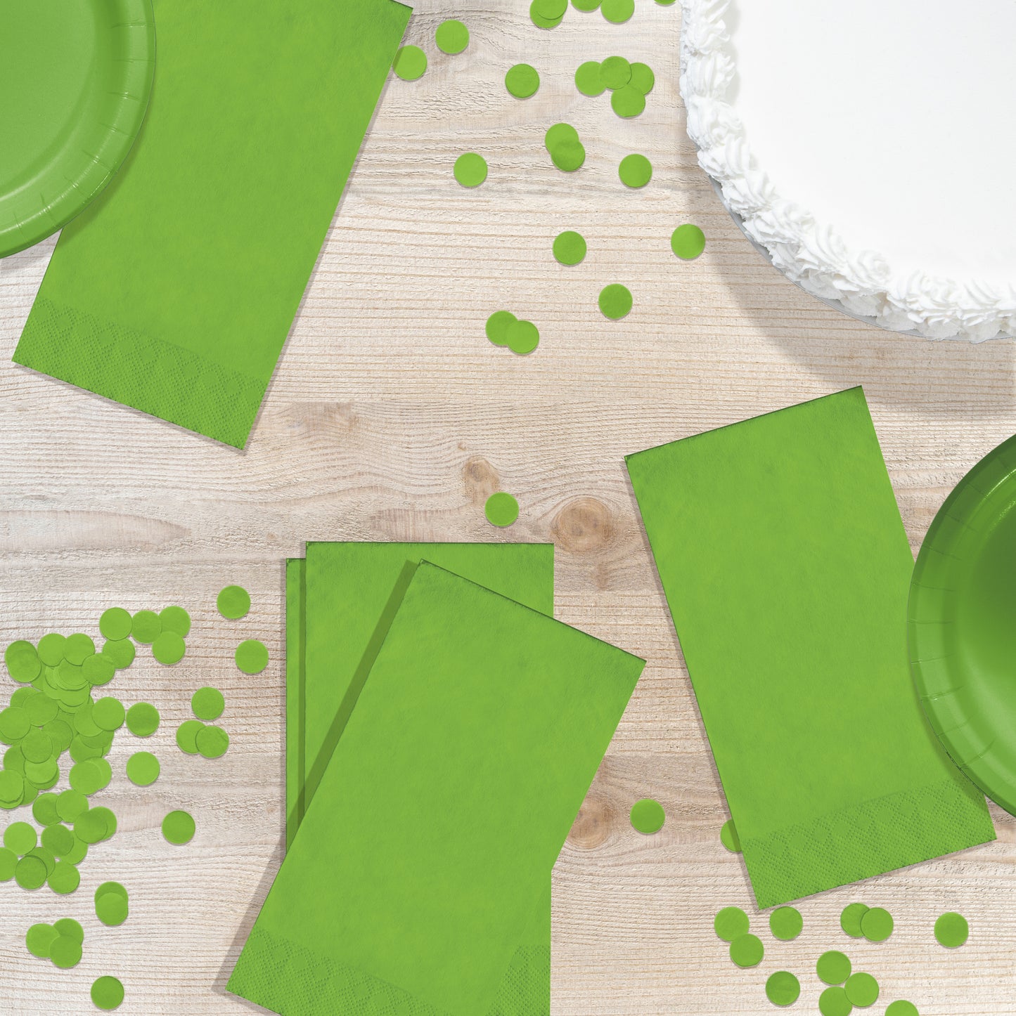 Green paper plates and napkins with green confetti on a wooden surface
