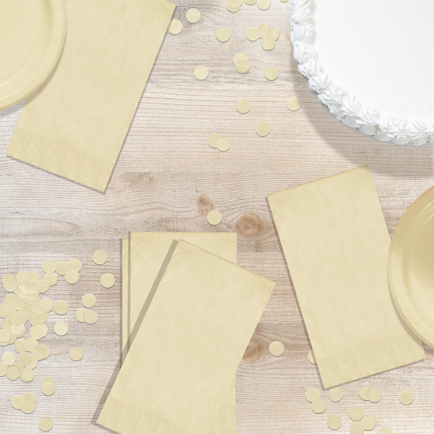 Ivory pin embossed napkins on a wood table with confetti and a white cake