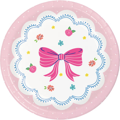 Round pink plate with a decorative bow and floral design on a white background