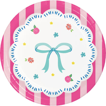 Round paper plate with pink and white striped border, white center with blue bow and flowers, on a white background.