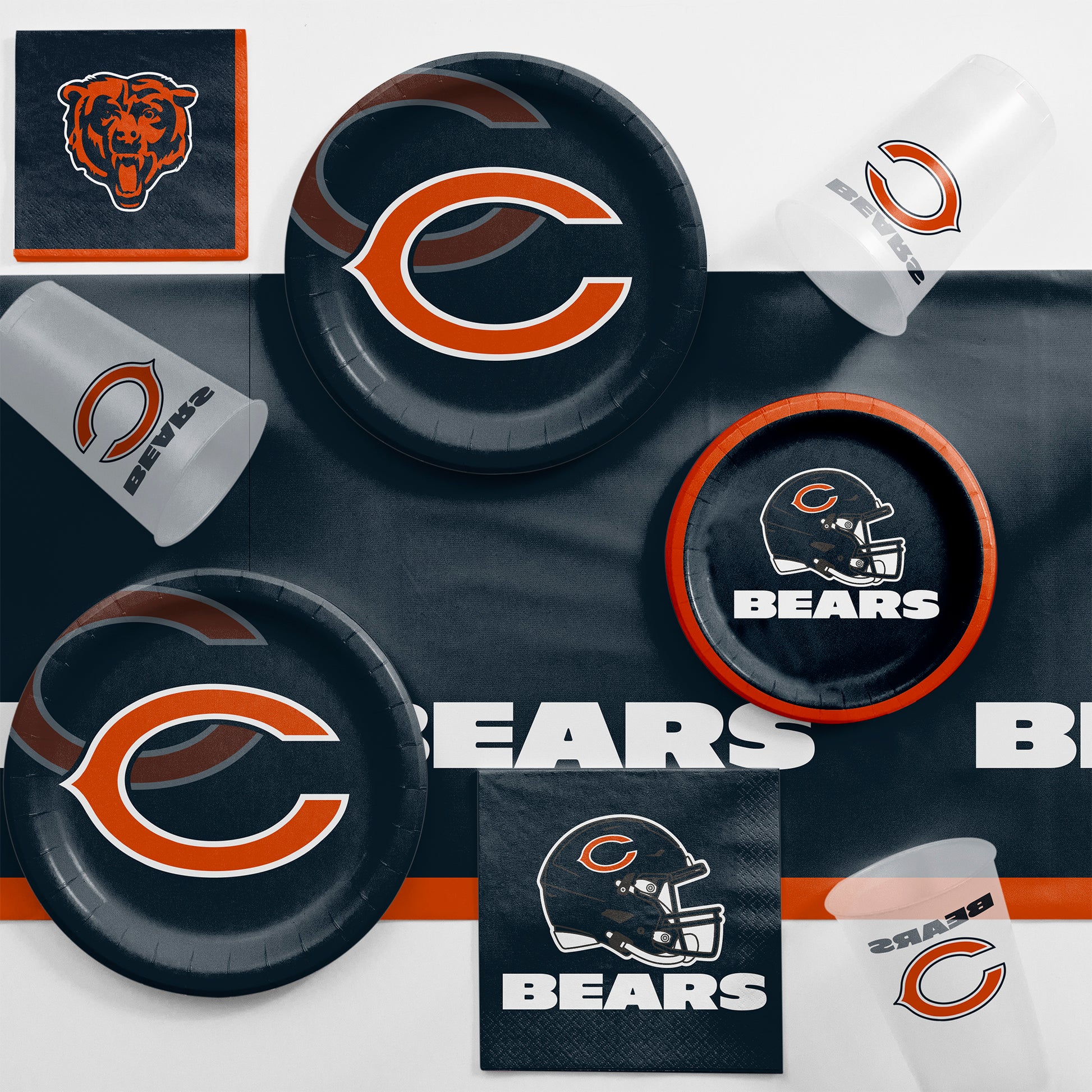 Collection of Chicago Bears-themed party supplies including plates, cups, and napkins on a navy blue tablecloth.