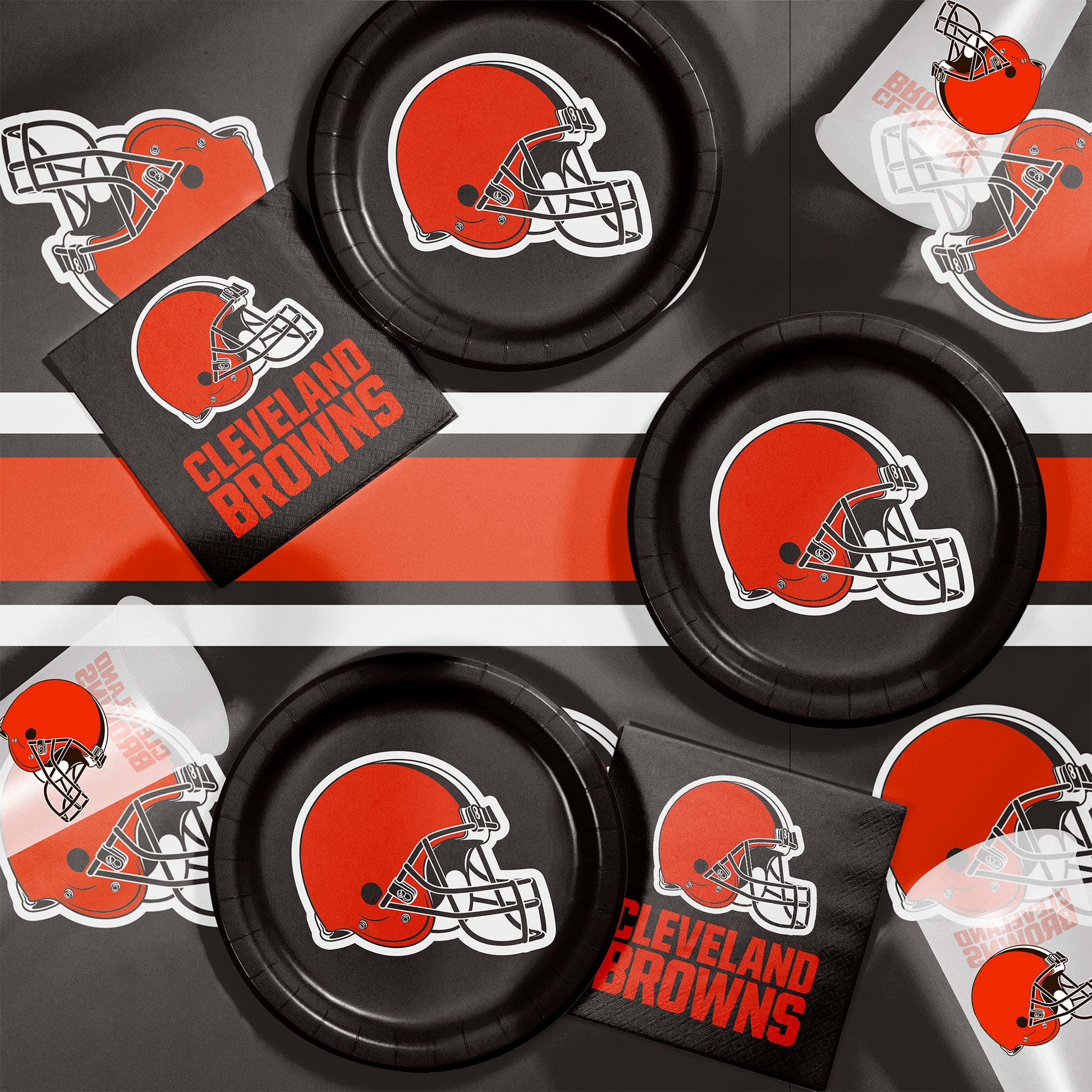 Cleveland Browns-themed party supplies including plates, napkins, and cups on a brown background.