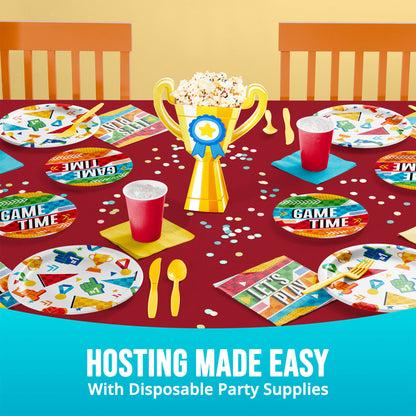 Disposable party supplies on a table with 'Game Time' plates, cups, and a trophy.